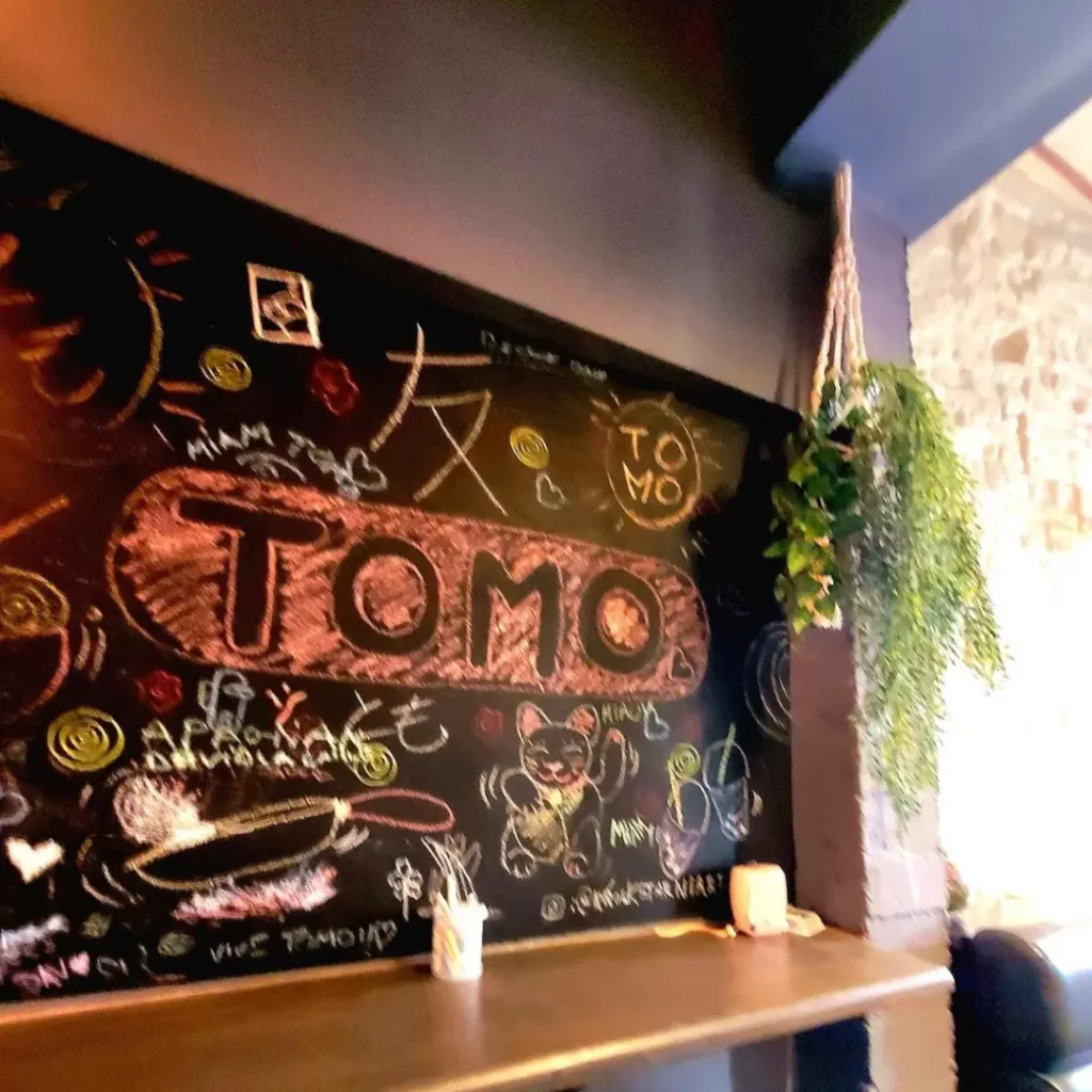 Art sur tableau noir avec 'Tomo' au restaurant Tomo Ramen à Mons, avec des designs créatifs.